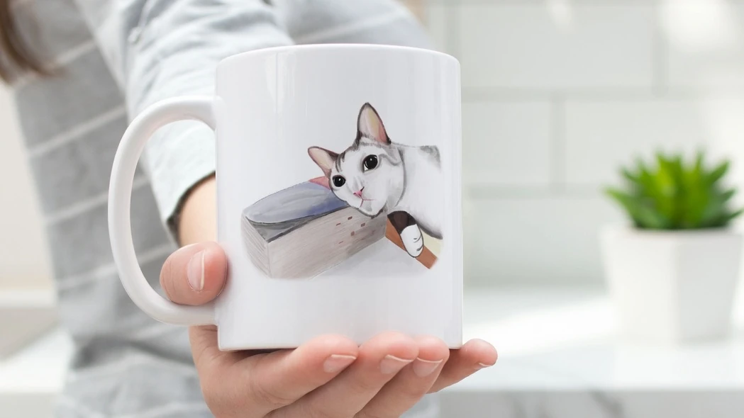 A custom pet portrait mug of a grey cat lying on a book..jpg