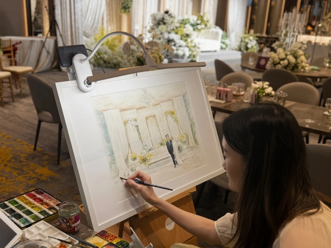 Live wedding artist adding final details to a custom couple painting at Anggun on Marina One.
